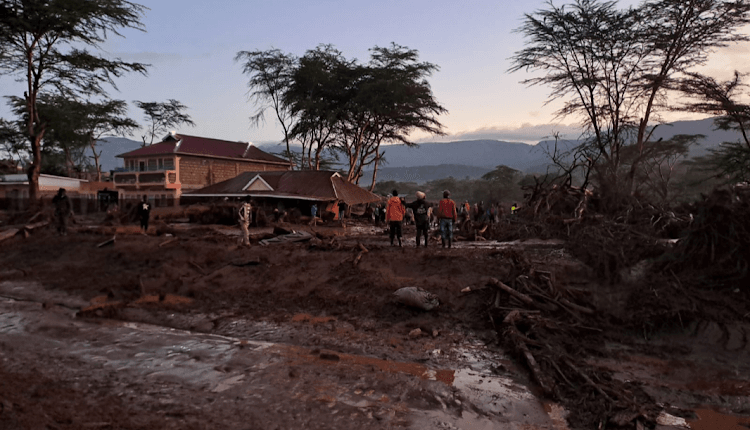People inspect a house damaged by raging flood waters at Kamuchiri village in Mai Mahiu.